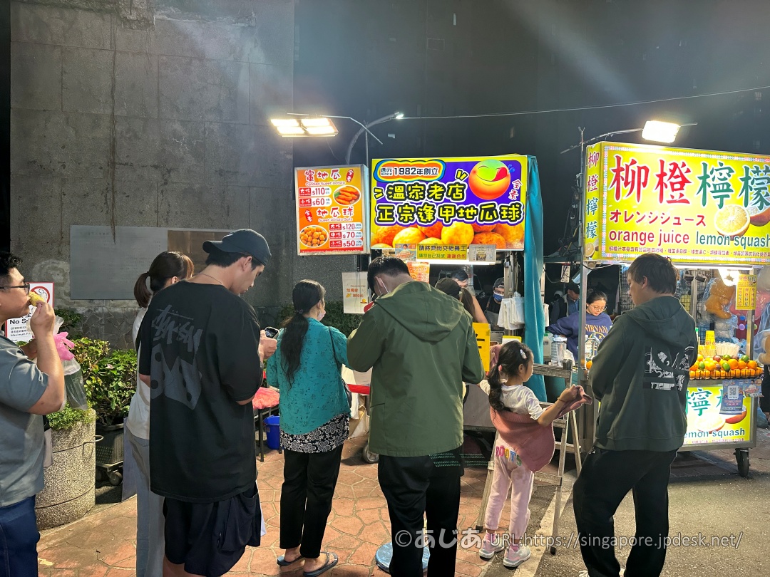 溫家老店 正宗逢甲地瓜球の屋台の前に並んで待つ複数のお客さんの後ろ姿