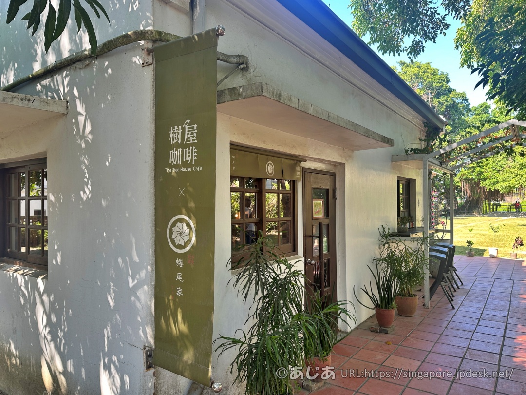 樹屋咖啡の白い外観と、入り口に掛けられた緑色のタペストリー