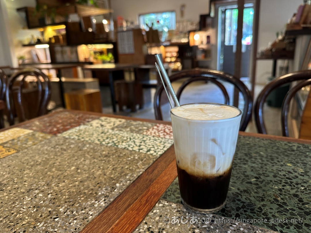 モザイクタイルのテーブルに置かれたグラス入りの冷たいカフェラテ