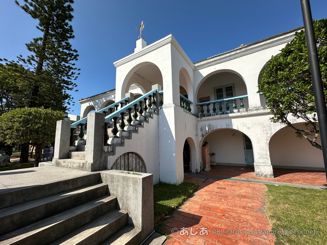 アーチ型の柱や青い手すりの階段が特徴的な、白亜のコロニアル建築「徳記洋行」の外観