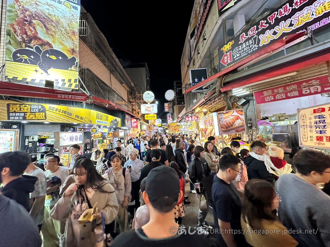 両側に看板が並ぶ逢甲夜市の混雑した通りを歩く大勢の人々