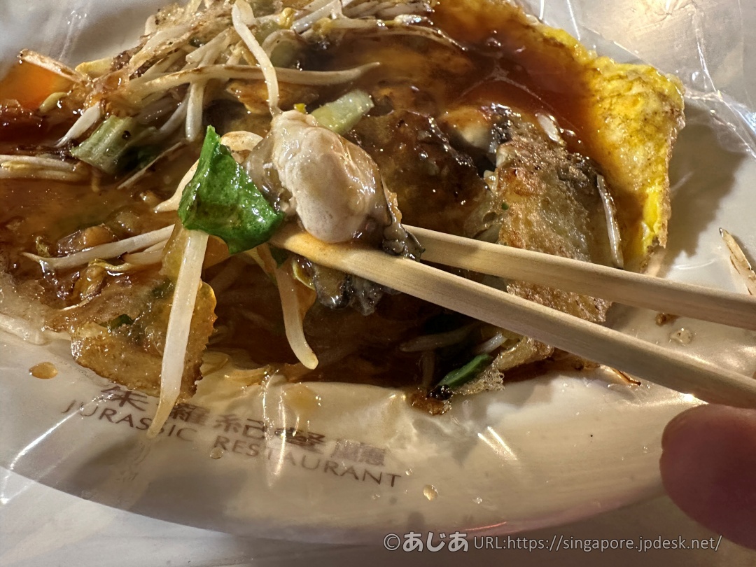 箸で持ち上げられた牡蠣と蚵仔煎のアップ写真