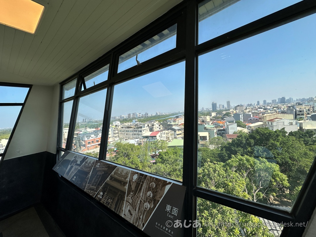 展望台の窓から見下ろす緑豊かな木々と安平の街並み、遠くに見える海