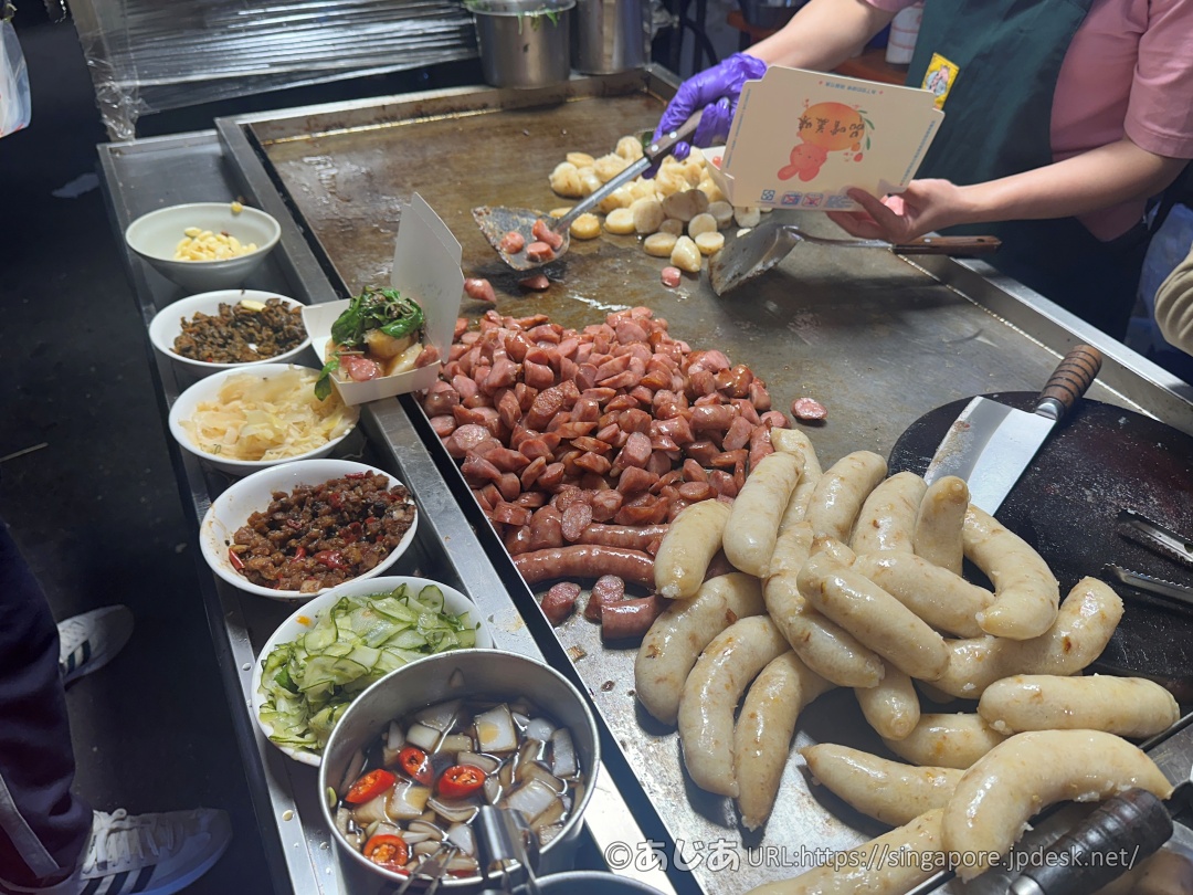 鉄板で調理中の大量のソーセージともち米腸、手前にはトッピングの具材