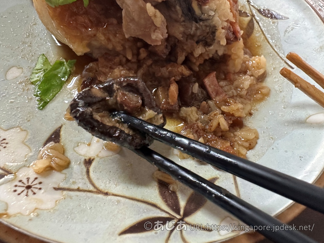 特製八寶肉粽の中から出てきた大きなしいたけをお箸で持ち上げているアップ