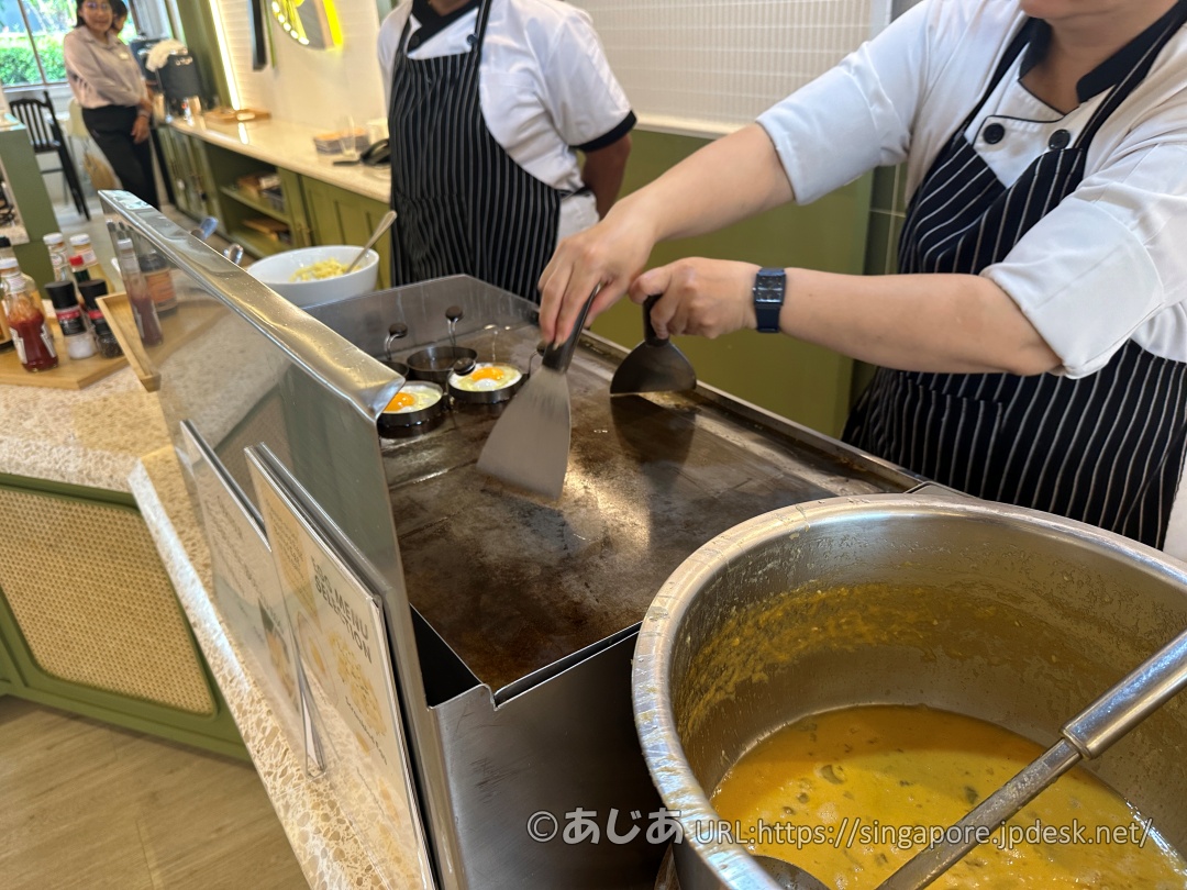 鉄板の上で目玉焼き用の丸い型を使って卵を焼いているシェフの手元。