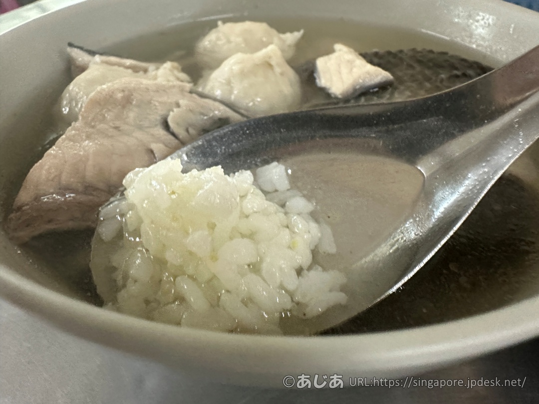 スープがたっぷり入ったどんぶりの中で、レンゲに乗せた白ご飯をスープに浸している様子