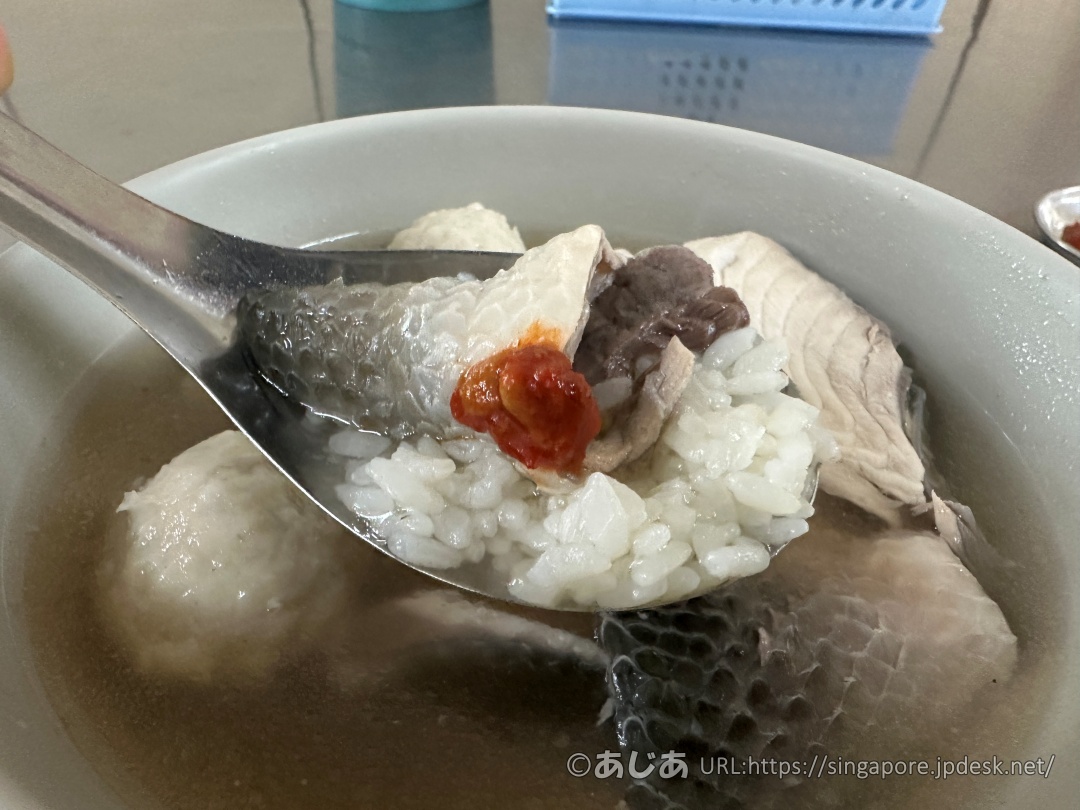 レンゲの上に白ご飯、魚皮、そして赤い辛味調味料を乗せている様子