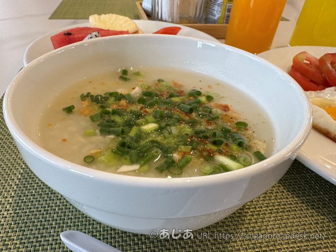 白いボウルに入ったお粥。たっぷりの青ネギと少しの唐辛子がトッピングされている。