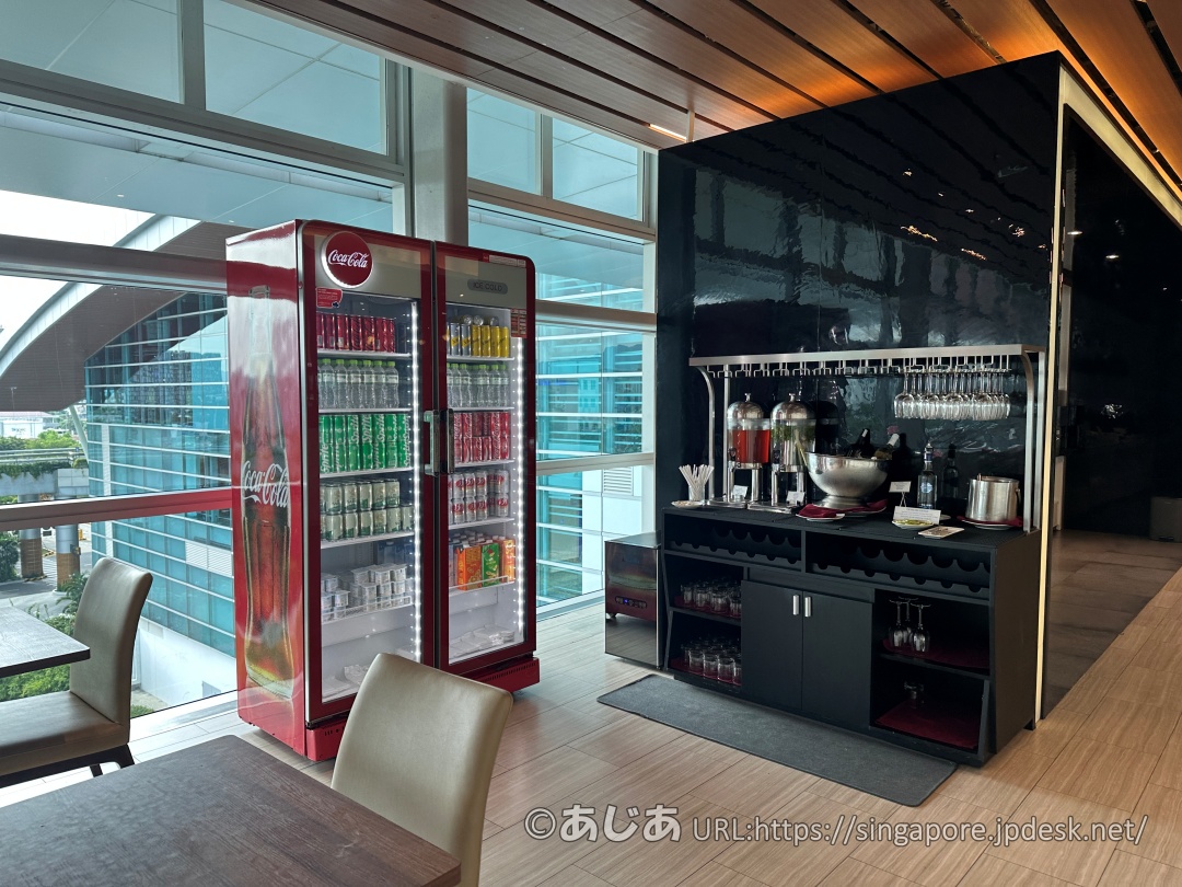 CIP Orchid Loungeのソフトドリンク用冷蔵庫とアルコールが並ぶドリンクカウンター