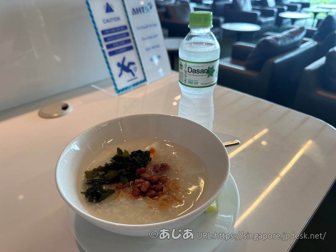 トッピングが乗ったコンジー（おかゆ）とDasaniのミネラルウォーター