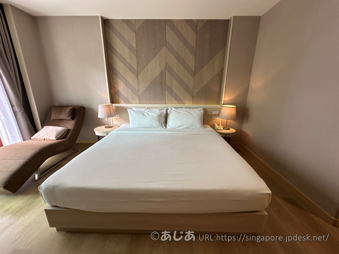 真っ白なシーツが掛けられた大きなキングサイズベッドと、両サイドのナイトテーブル。