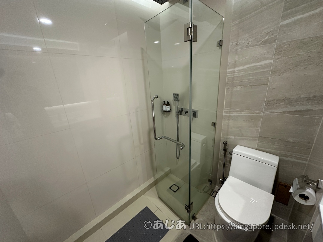 アレカロッジのバスルーム内観。ガラス張りのシャワーブース、白いトイレとトイレットペーパー。