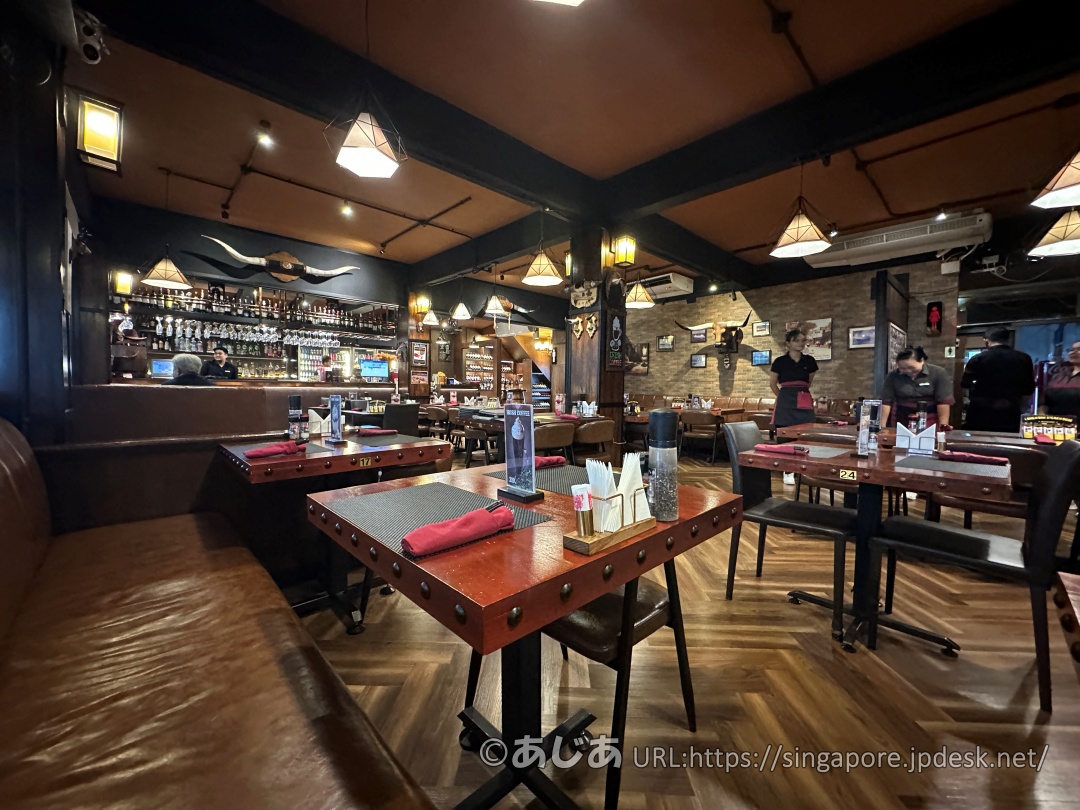 ダークブラウンのレザーソファとスタッズがあしらわれた木製のテーブルが並ぶ、ウエスタン風の店内。壁には牛の角のオブジェが飾られている。