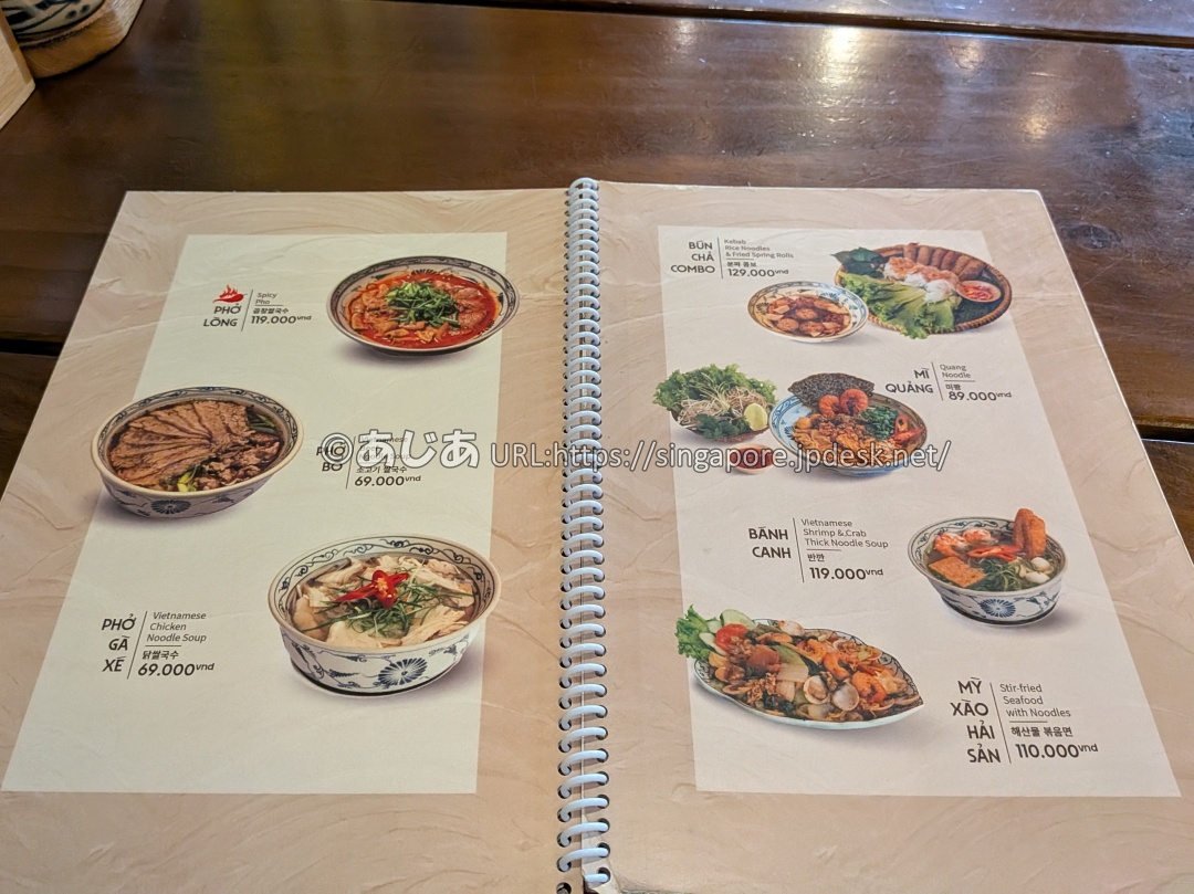 メニューブックの麺類のページ。フォー、スパイシーフォー、ブンチャーコンボ、ミークアンなどの写真と価格が記載されている。