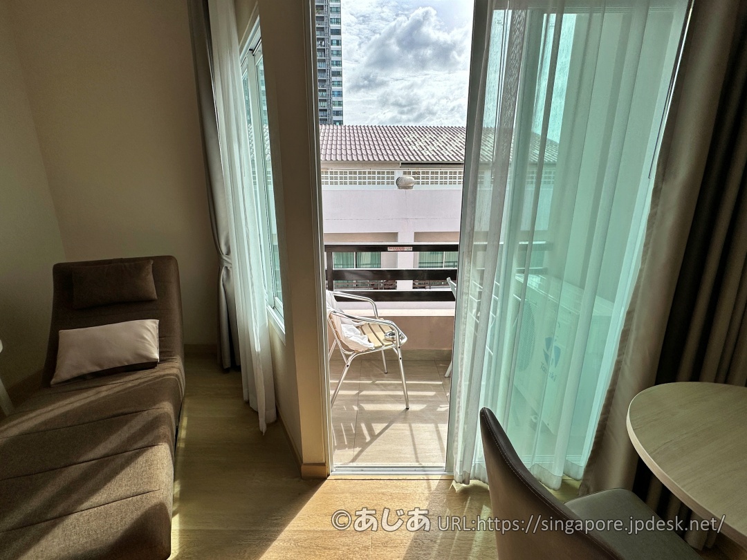 窓ガラス越しに見えるバルコニー。椅子が置かれている。