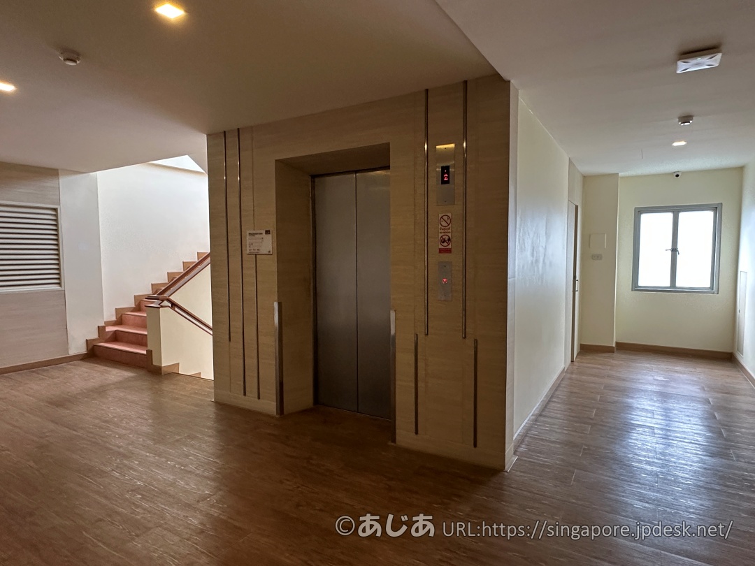 アレカロッジのエレベーターホール。木目調の床とシンプルな壁面。