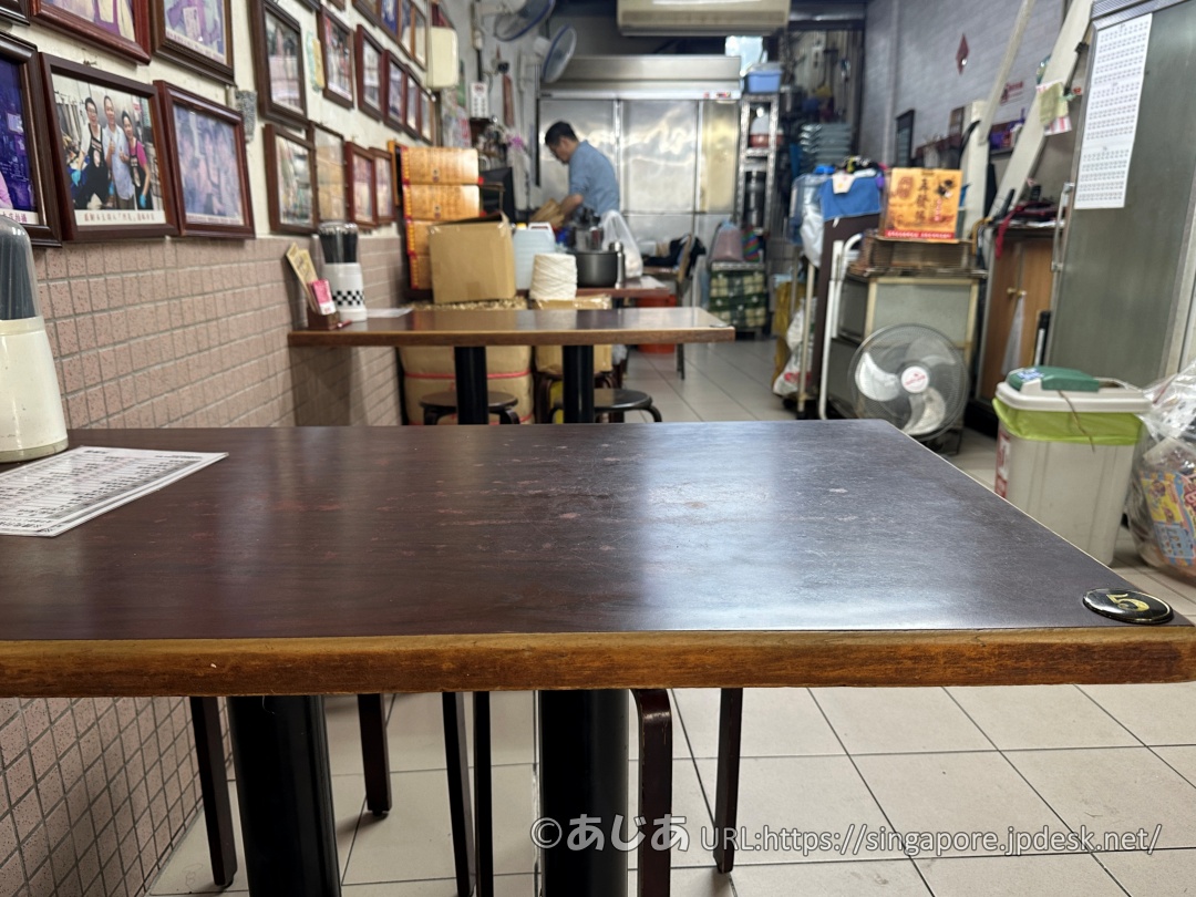 再發號百年肉粽の店内の様子。茶色いテーブルと椅子が並び、奥でスタッフが作業をしている