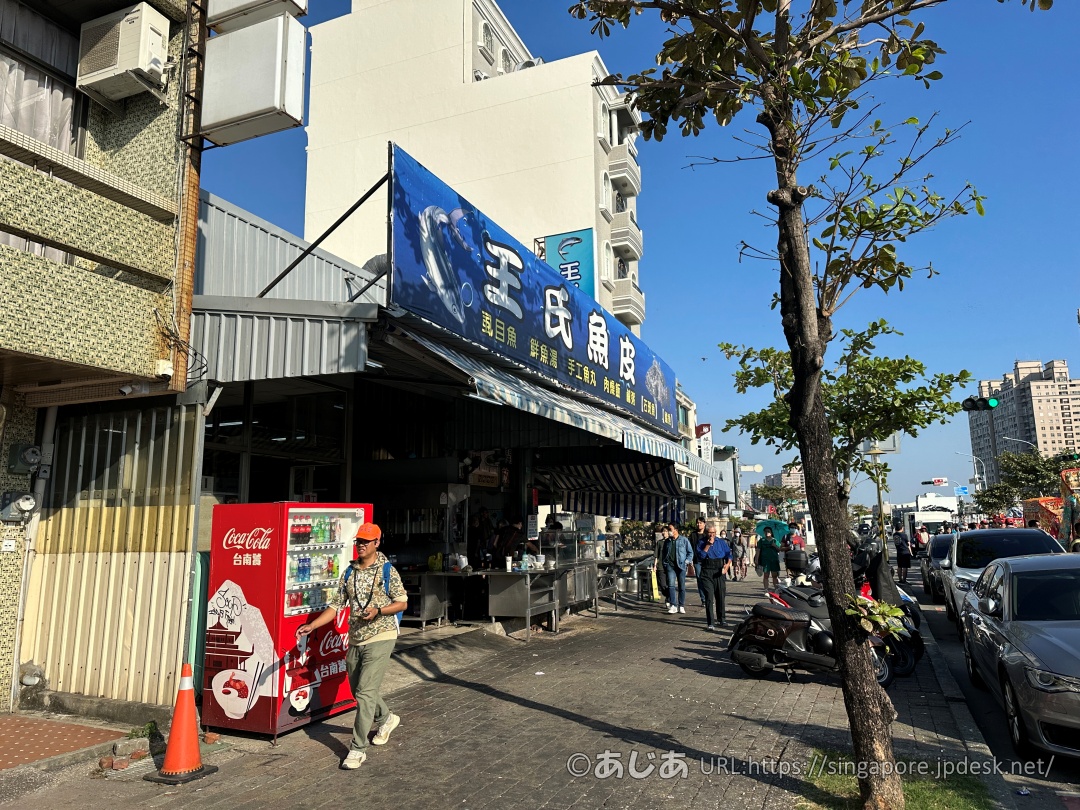 王氏魚皮の店舗前の歩道の様子。赤いコカ・コーラの自動販売機と歩く人々