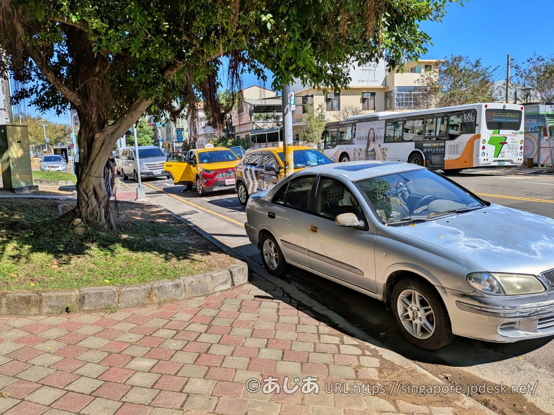 彩虹眷村近くの道路に停車している複数台の黄色いタクシーやシルバーの乗用車、乗り降りする人々の様子