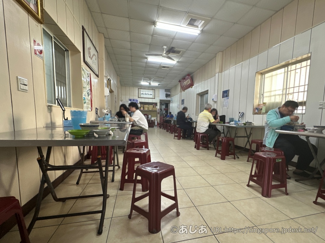 王氏魚皮の店内の様子。ステンレスのテーブルと赤いプラスチック椅子に座って食事をするお客さんたち