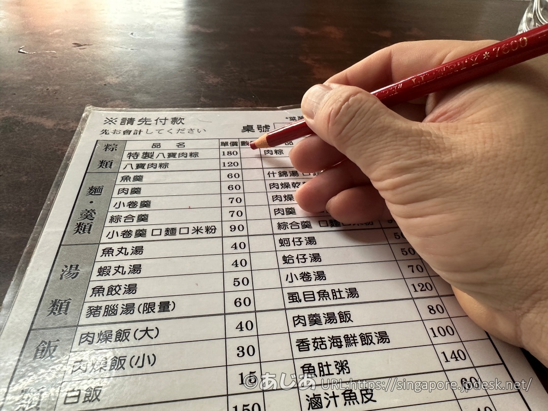 注文シートの「特製八寶肉粽」の欄に、赤い色鉛筆で数量を書き込んでいる様子