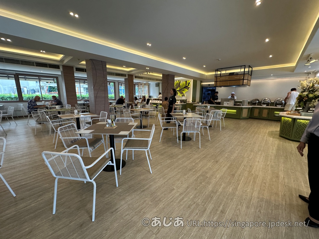 アレカロッジの朝食レストラン内観。木の床に白い椅子とテーブルが並び、奥にビュッフェコーナーが見える。