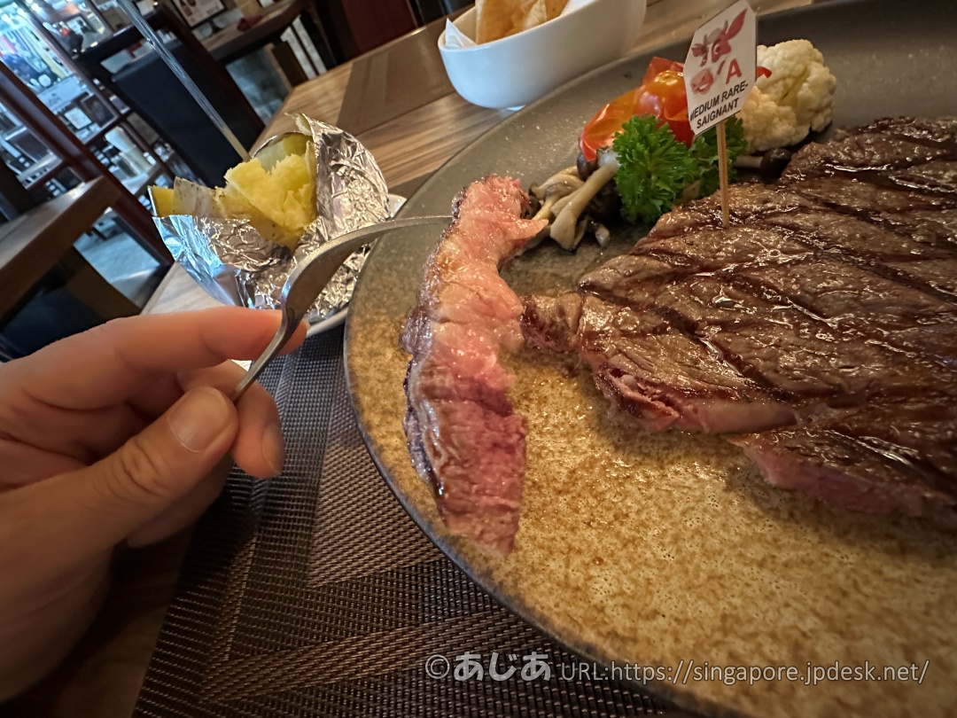 フォークで持ち上げられたステーキの断面。外側はこんがり、内側はしっとりとした美しいピンク色のミディアムレア。