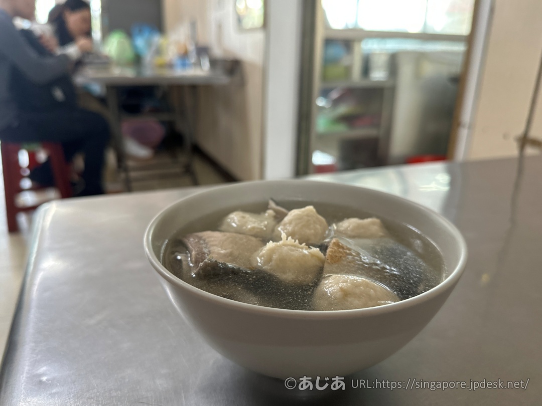 ステンレスのテーブルの上に置かれた、魚皮とつみれがたっぷり入った「魚皮加丸湯」のどんぶりのアップ