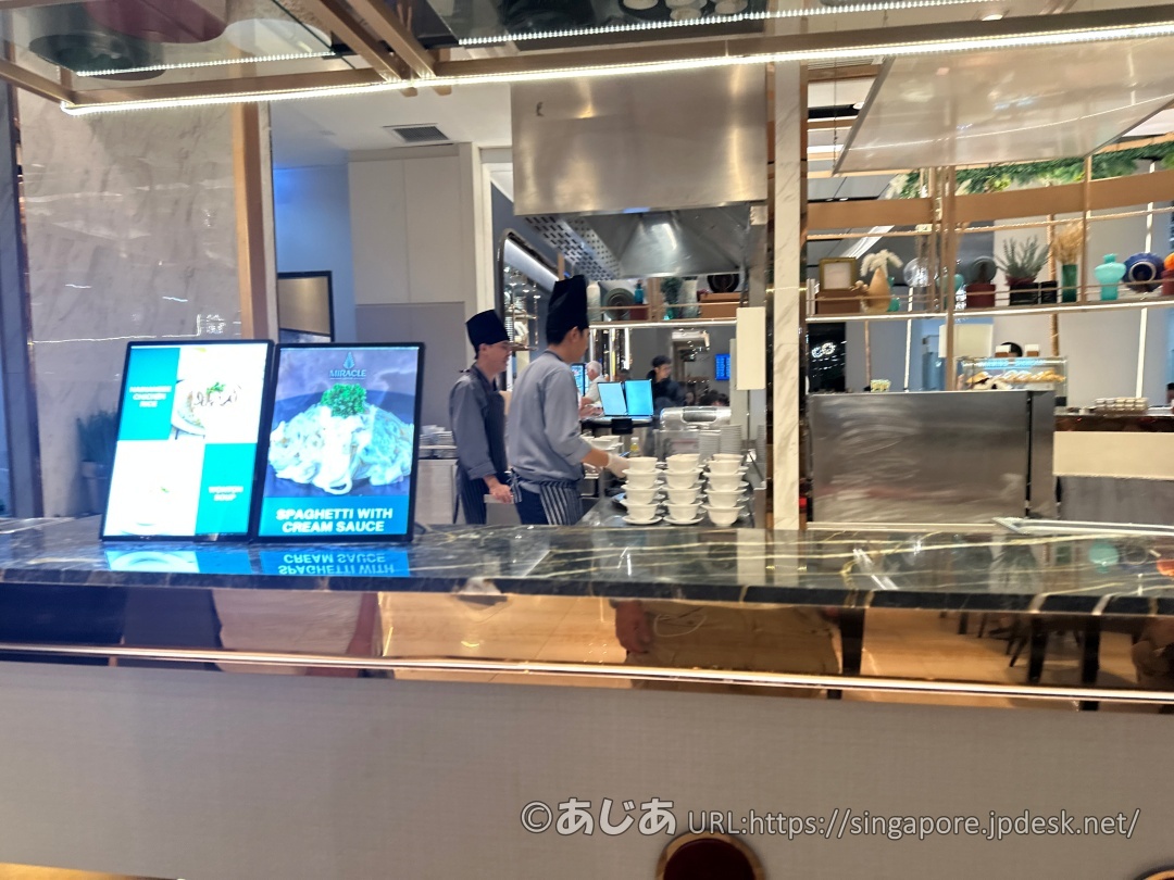 ガラス張りのキッチンスペースで、シェフの帽子をかぶったスタッフが調理している様子。