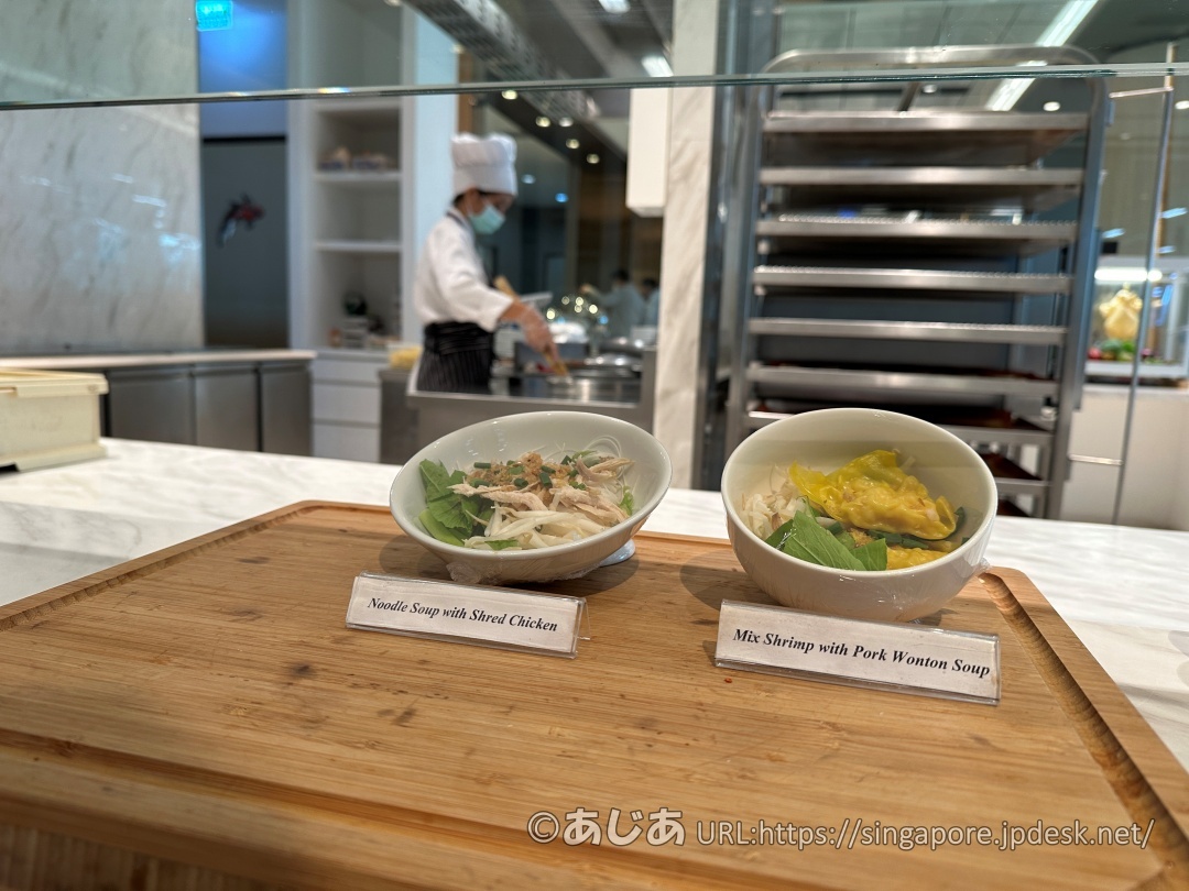 木のボードの上に置かれた2種類のスープ麺のサンプル。それぞれ「Noodle Soup with Shred Chicken」「Mix Shrimp with Pork Wonton Soup」と書かれた札がある。