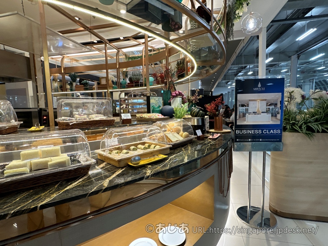 大理石調のカウンターの横に「BUSINESS CLASS」と書かれた青い案内板が立っている様子。奥には隣のラウンジの空間が見える。