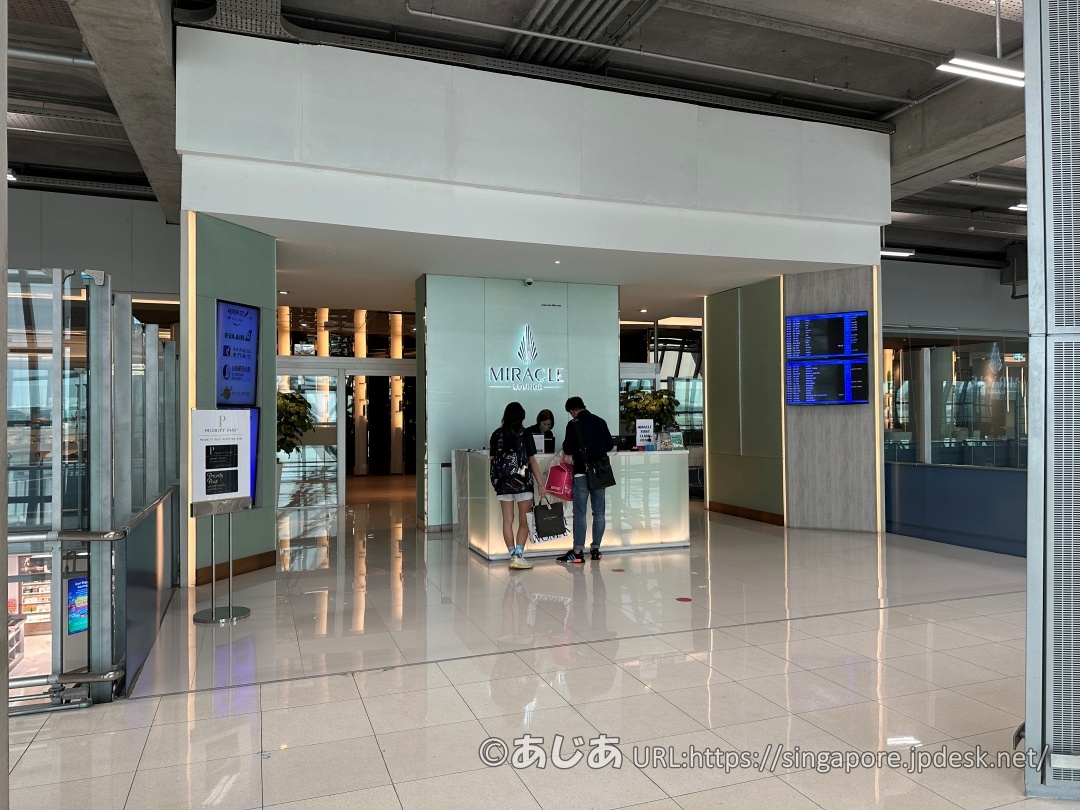 Miracle Loungeの受付エントランス。ライトグリーンの壁にMIRACLEのロゴが光り、利用客が受付をしている様子。