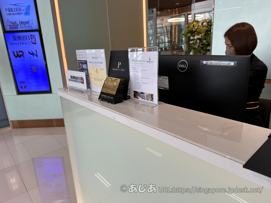 ラウンジの受付カウンターのアップ。PRIORITY PASSの黒い立て札やその他の利用可能カードの案内が並んでいる。