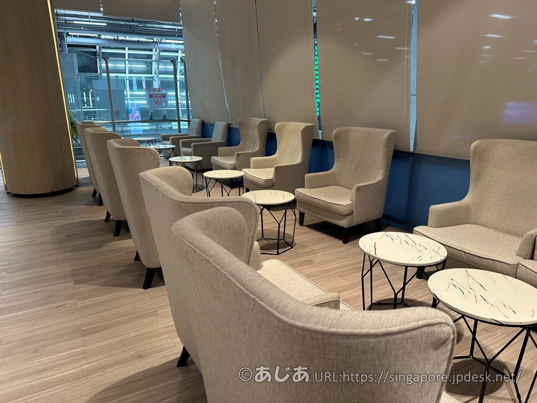 明るい窓際に並べられたライトグレーのハイバックチェアと、大理石調の丸いカフェテーブル。