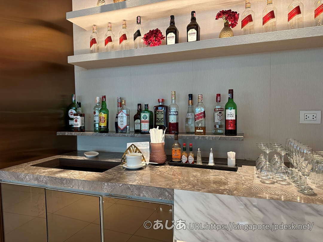 棚に並んだ様々な種類のリキュールやスピリッツ、ワイングラスが用意されたアルコール・バーカウンター。