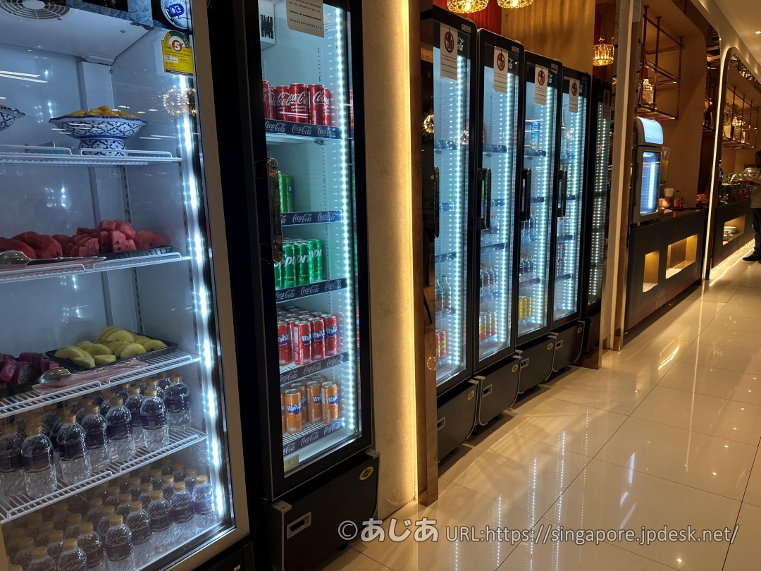 ラウンジ内の冷蔵庫。ソフトドリンクやミネラルウォーターの缶・ペットボトル、カットされたスイカやパイナップルが並んでいる。