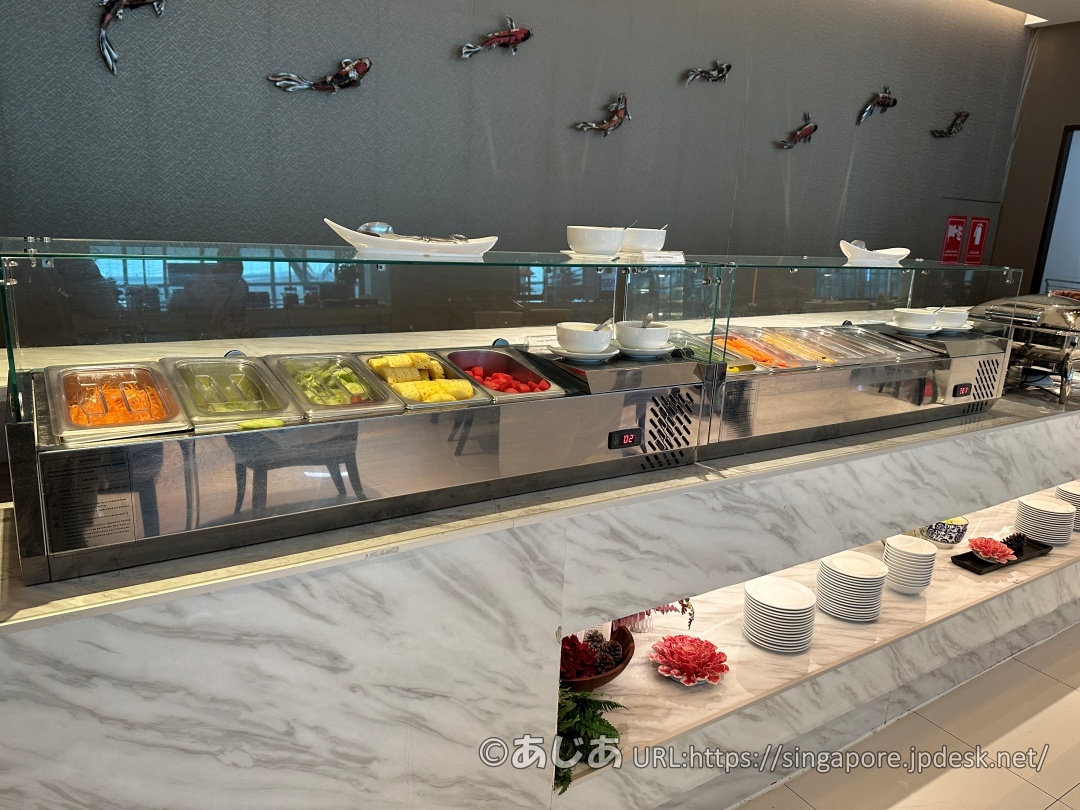 ガラス張りの保冷ケースに並んだ、ニンジンやレタスなどのサラダバー用のカット野菜。