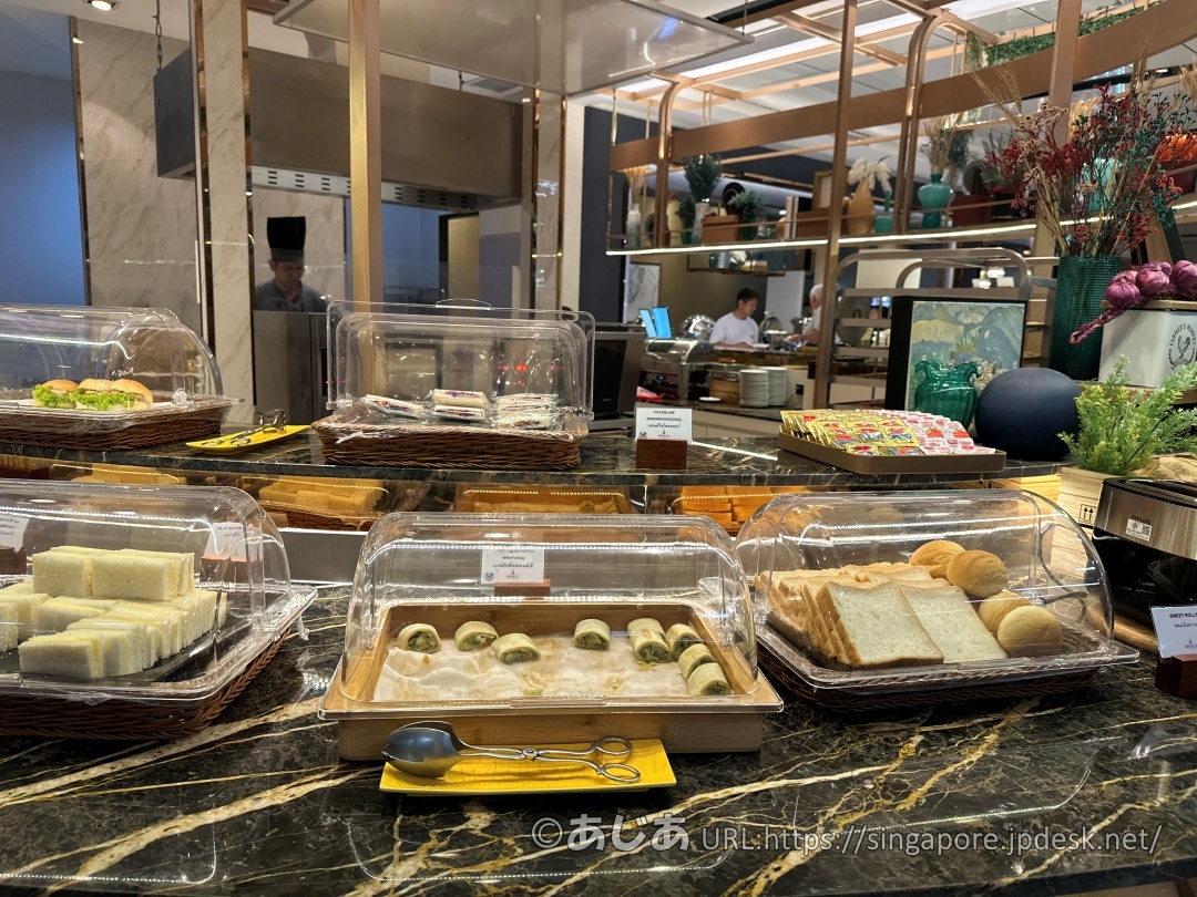 透明なカバーがかけられたサンドイッチ、ロールケーキ、食パンなどが並ぶ軽食コーナー。