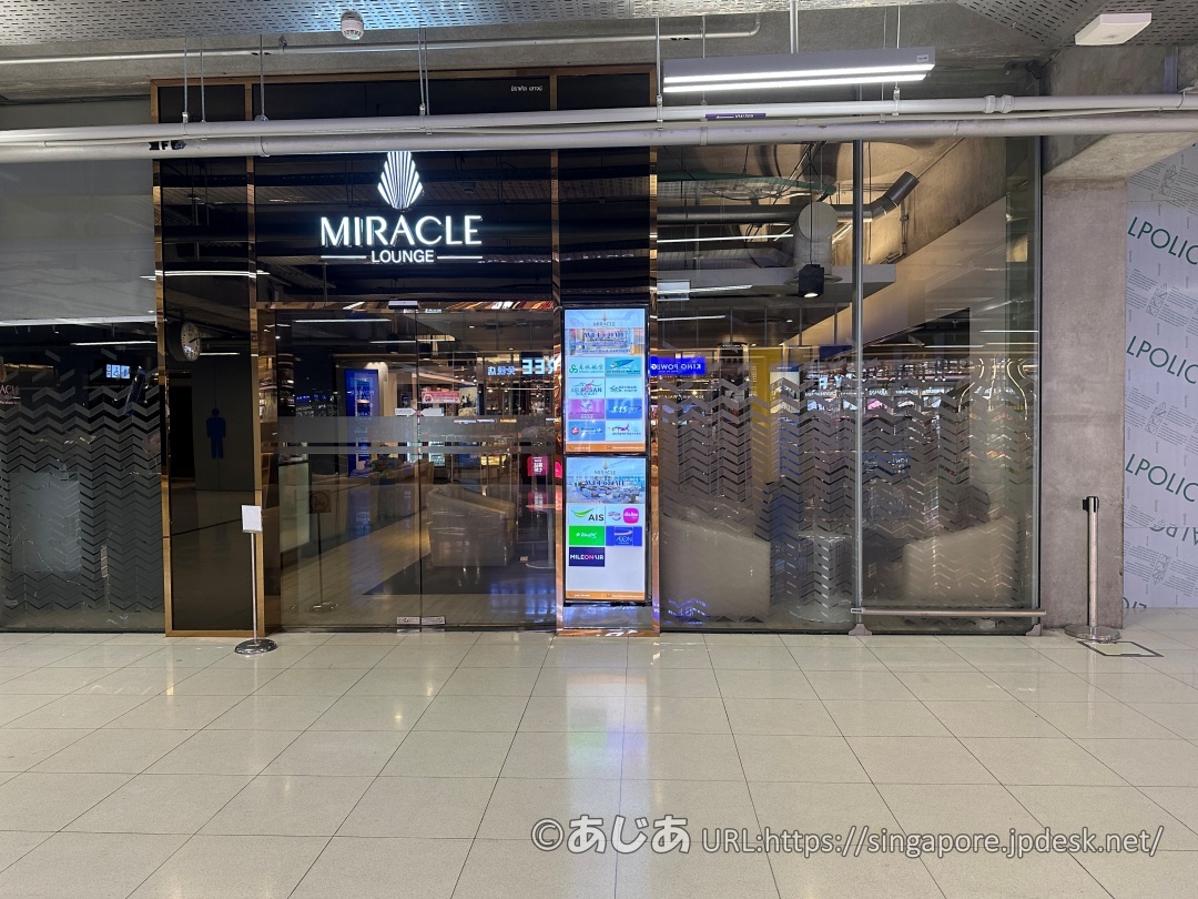 ガラス張りの外観にMIRACLE LOUNGEのロゴがあるラウンジ入り口。横には提携カードなどのデジタル看板がある。
