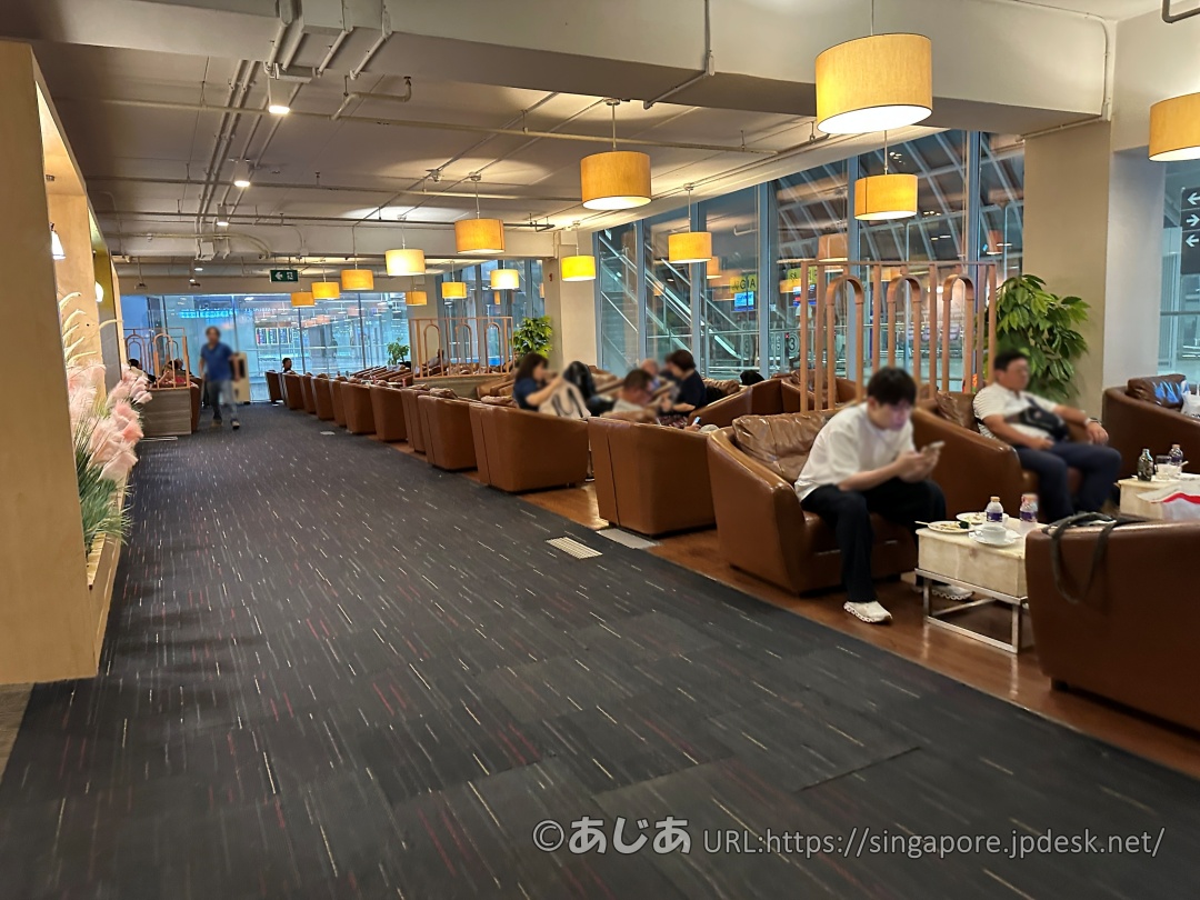 茶色いレザー調のソファーが並ぶビジネスクラスラウンジの内観。天井には丸い間接照明が並んでいる。