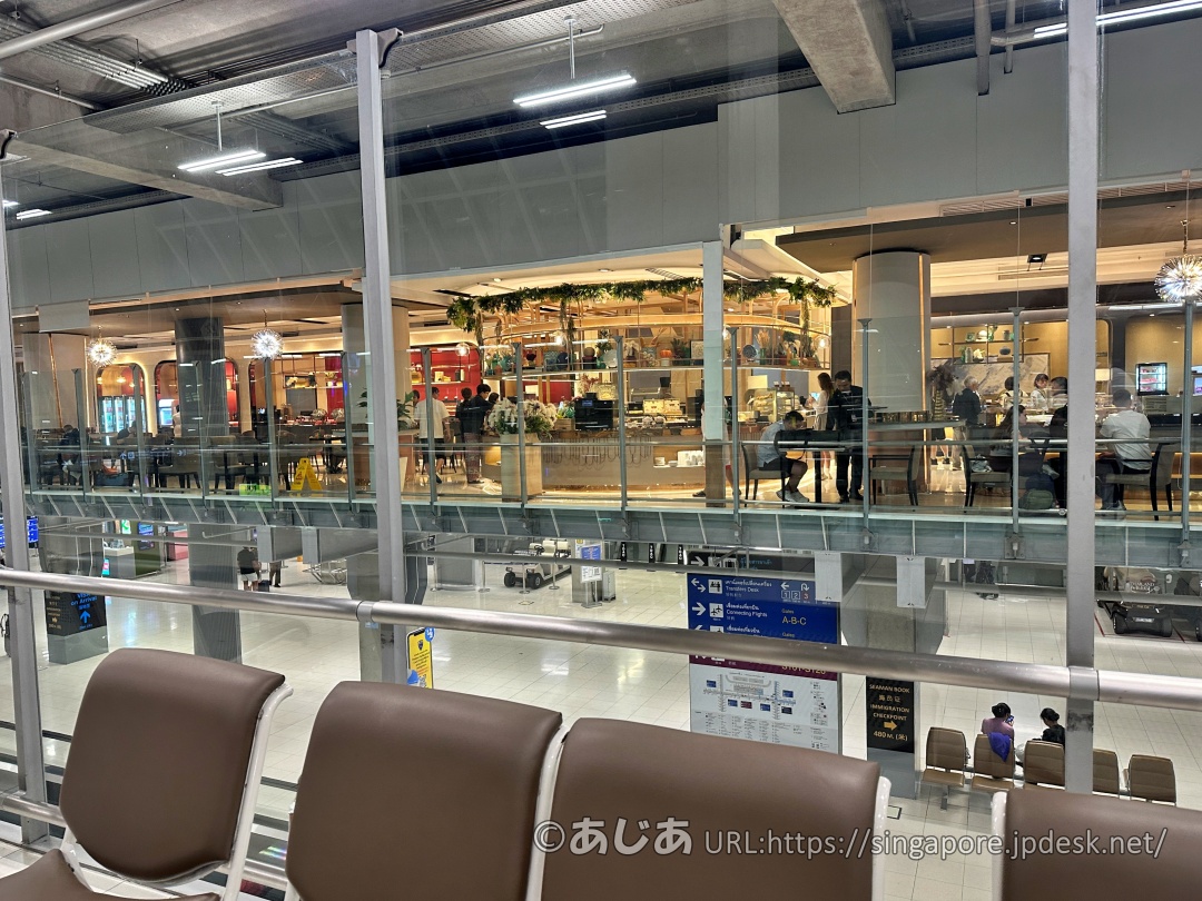 ターミナルの通路からガラス越しに見えるラウンジ内部の様子。ダイニングエリアに多くの人がいるのが見える。