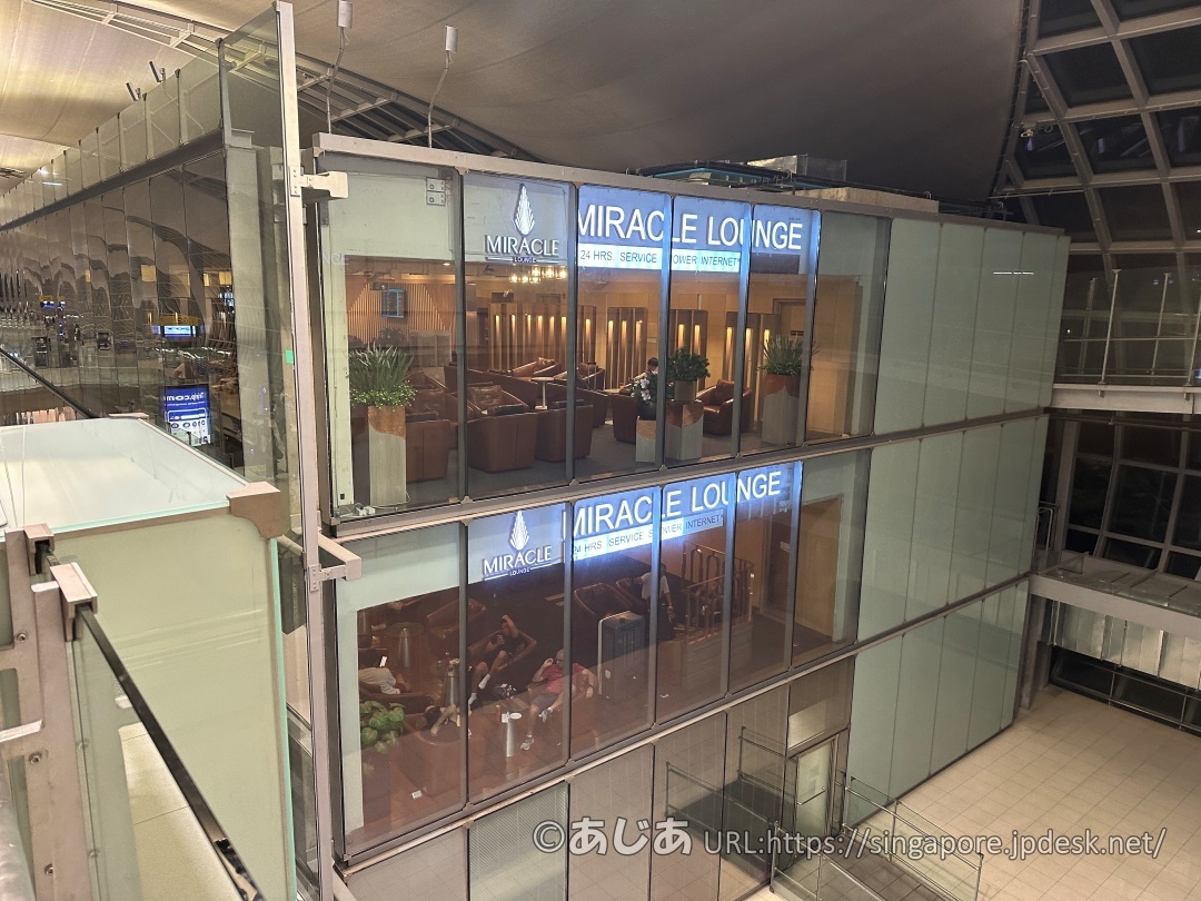 ガラス越しに見えるラウンジの窓枠。1階と2階の両方に「MIRACLE LOUNGE」の青いロゴサインが光っている。