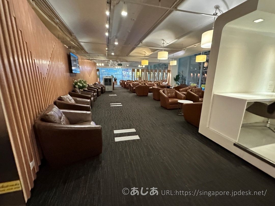 木目調の壁面に沿って、ブラウンの重厚なレザー調ソファーが等間隔に並んでいるラウンジの座席エリア。