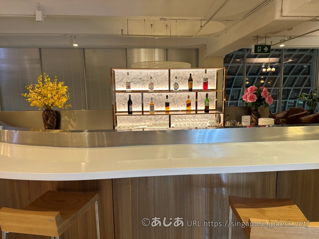 白いカウンターの奥にある、大理石調のバックライト付き飾り棚。数種類のウイスキーやリキュールのボトルが美しく並べられている。