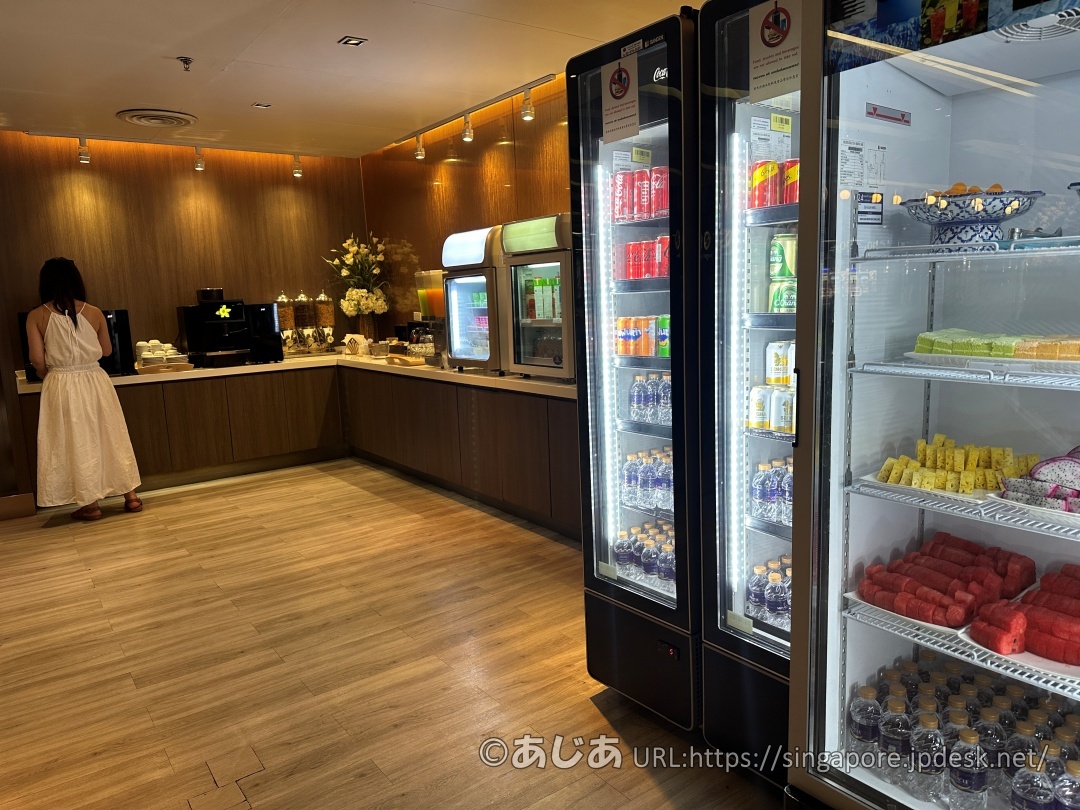 壁沿いに並んだドリンク冷蔵庫と、ケーキやフルーツが入った保冷ケース。その奥にはコーヒーメーカーなどが見える。