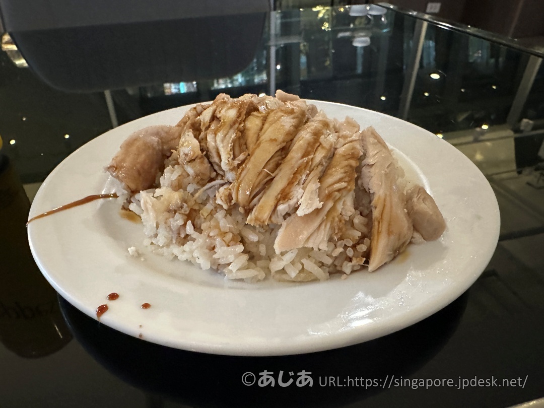 お皿に盛られたチキンライス。ご飯の上にスライスされた茹で鶏が乗り、タレがかかっている。