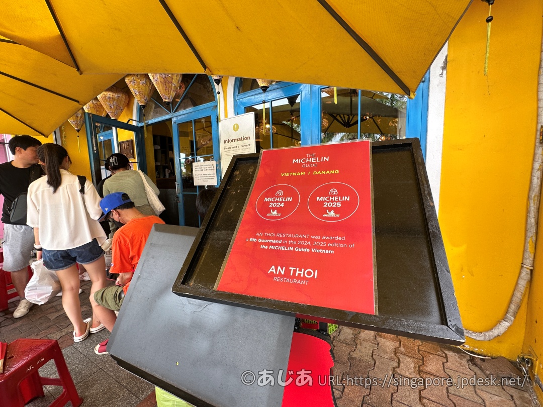 店先の黒いメニューボードに置かれた赤いミシュランの案内板。「MICHELIN 2024」「MICHELIN 2025」のマークとビブグルマン受賞の説明が書かれている。