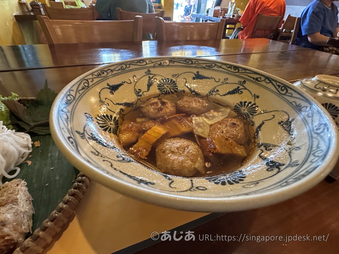 模様のある陶器のどんぶりに入ったスープ。中には丸い肉団子（つみれ）と、平たいさつま揚げのような具材が浸かっている。