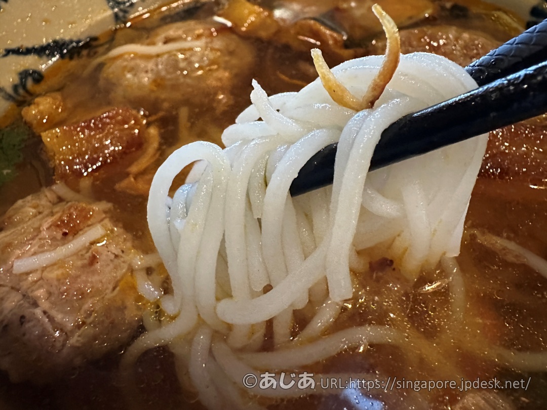 お箸で持ち上げられた白いブン（米粉麺）。奥にはスープに浸かった肉団子が見える。